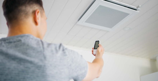 Kuvituskuva sähköaiheiseen artikkeliin. Kuvassa mies säätämässä kodin ilmastointilaitetta.